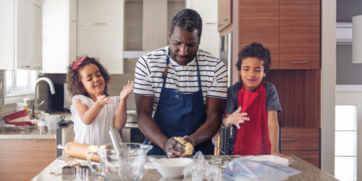 Father and two kids cook a homemade meal in their kitchen.