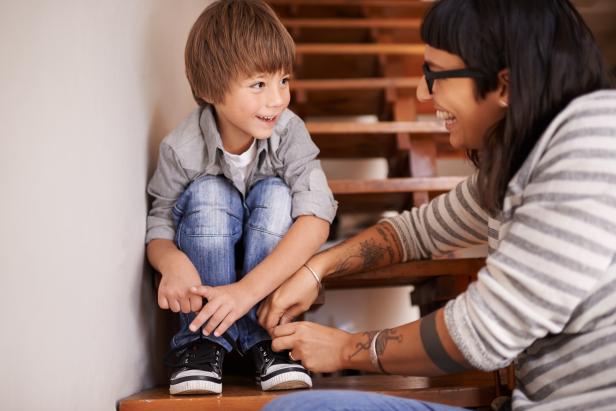 Mom helping young boy tie shoelaces