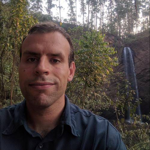 Dustin Dunsmuir standing in front of a waterfall in Uganda