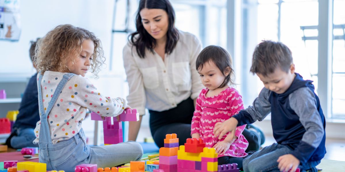 Child care employee sitting with a group of children