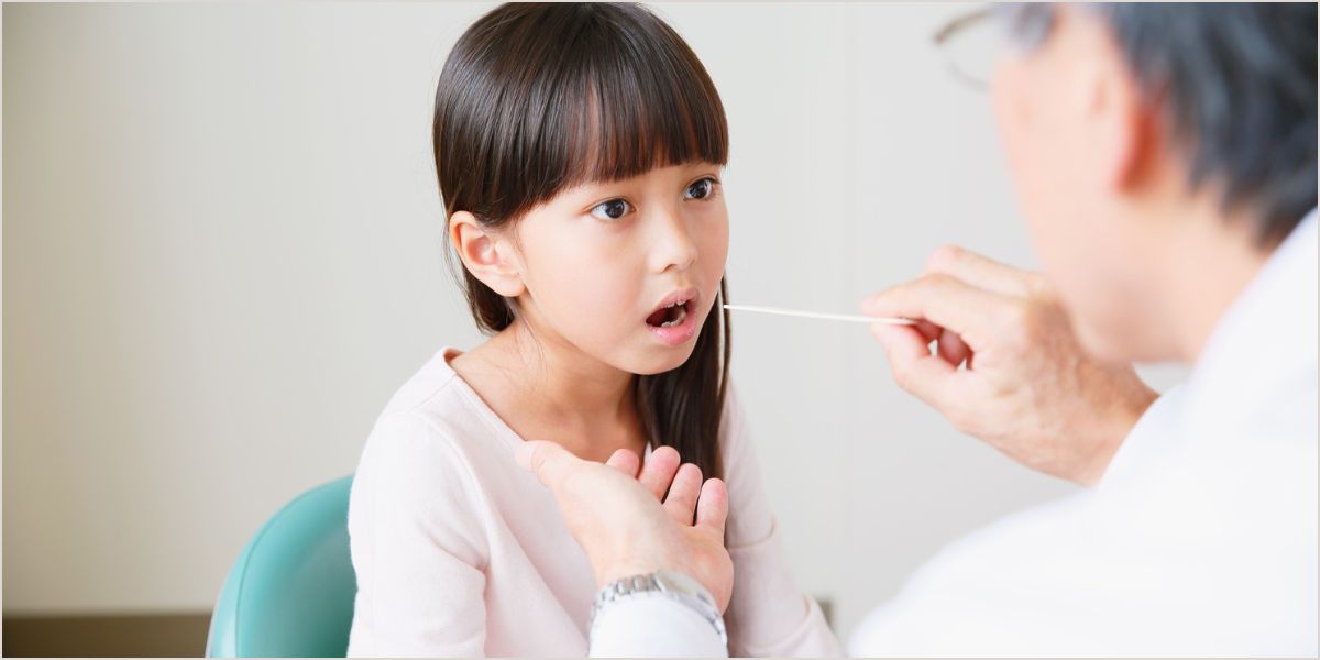 A stock photo of a doctor doing a throat swab.
