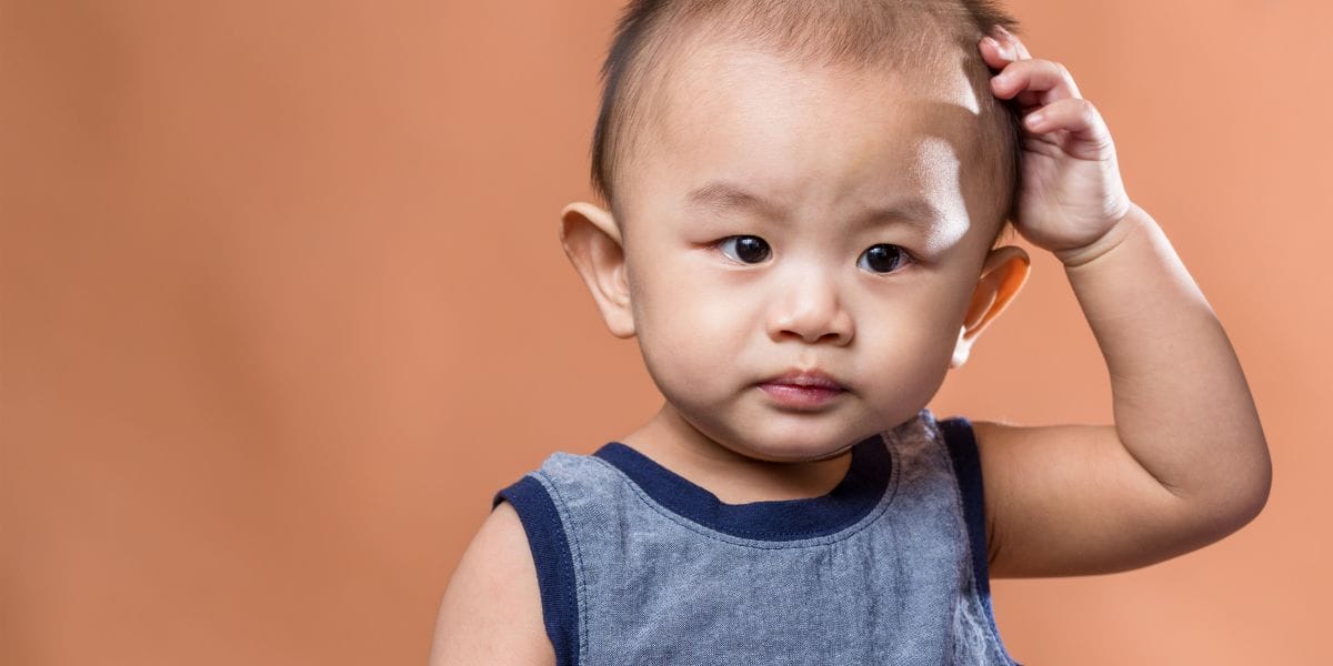 Young male child holding their head